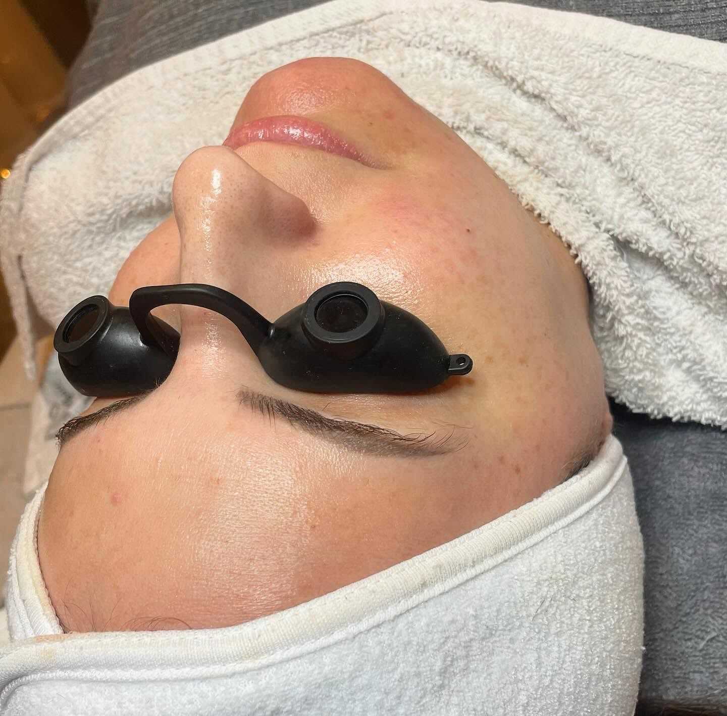 Person lying down with protective goggles, ready for a facial treatment.