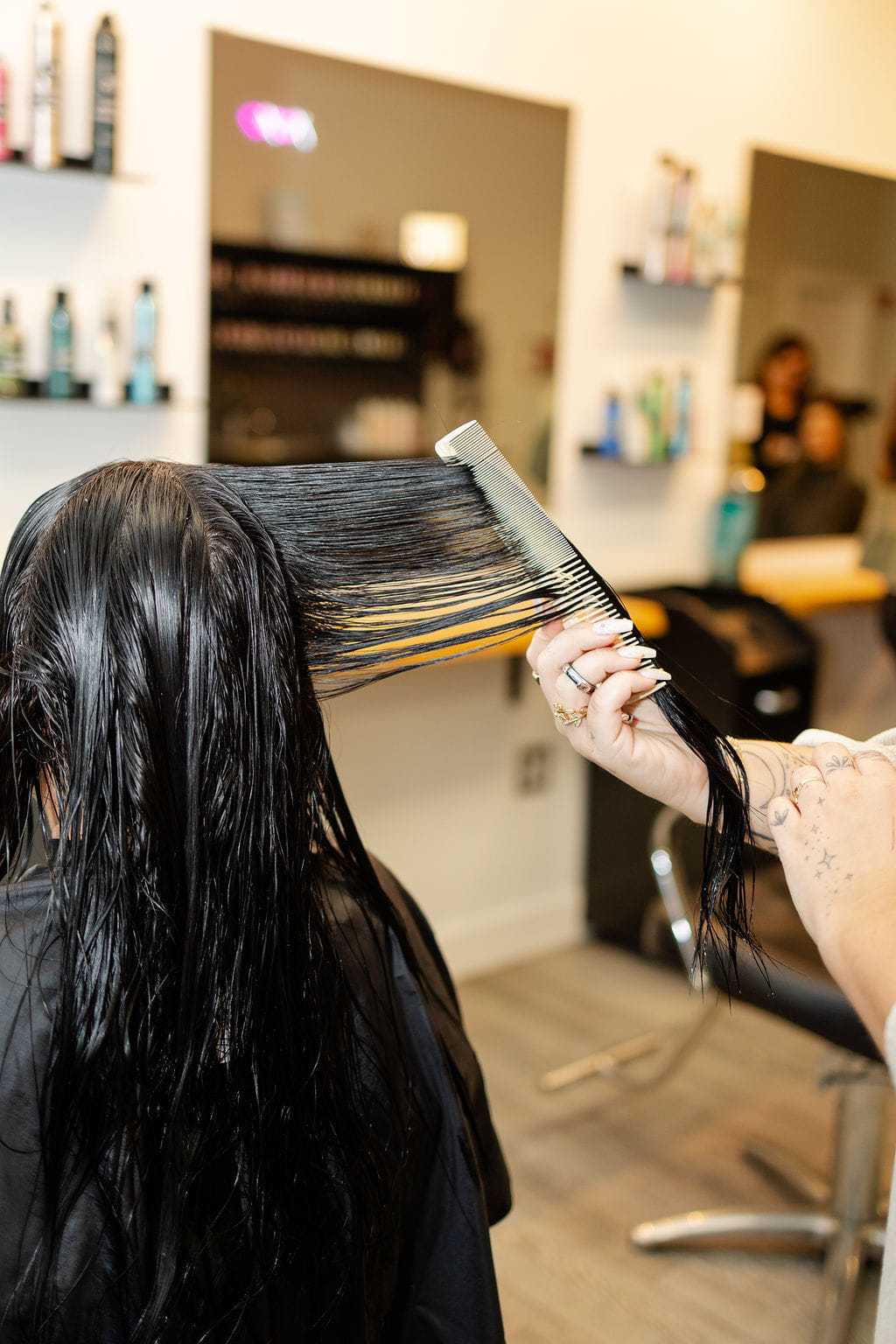 Stylist combing wet hair in a modern salon setting.